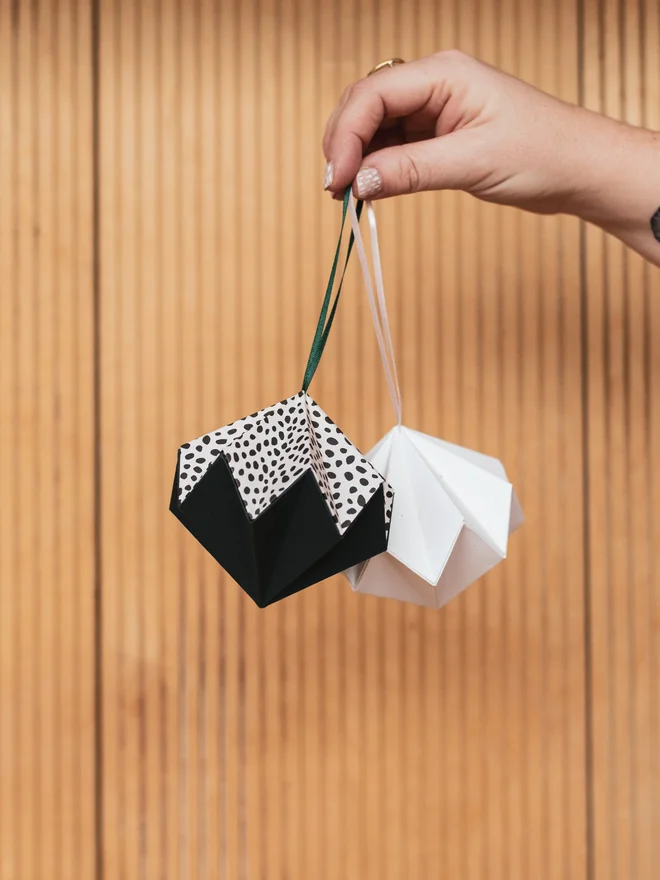 Woman's hand holding origami diamond ornaments from ribbon