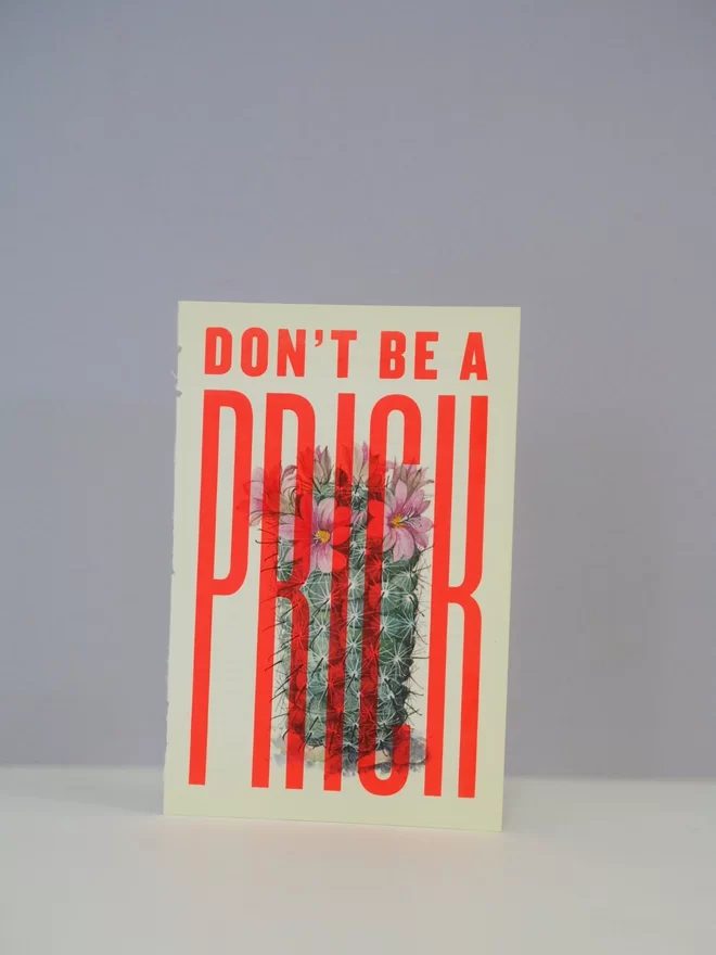 Photograph of a typographic screen print with the words 'don't be a prick' hand printed over a vintage book page featuring an illustration of a flowering cactus