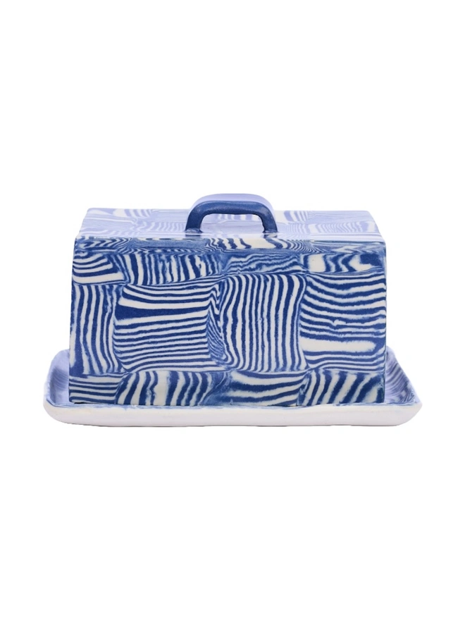 Striped Butter Dish, a colourful striped butter dish sitting on a white surface against a plain backdrop. 