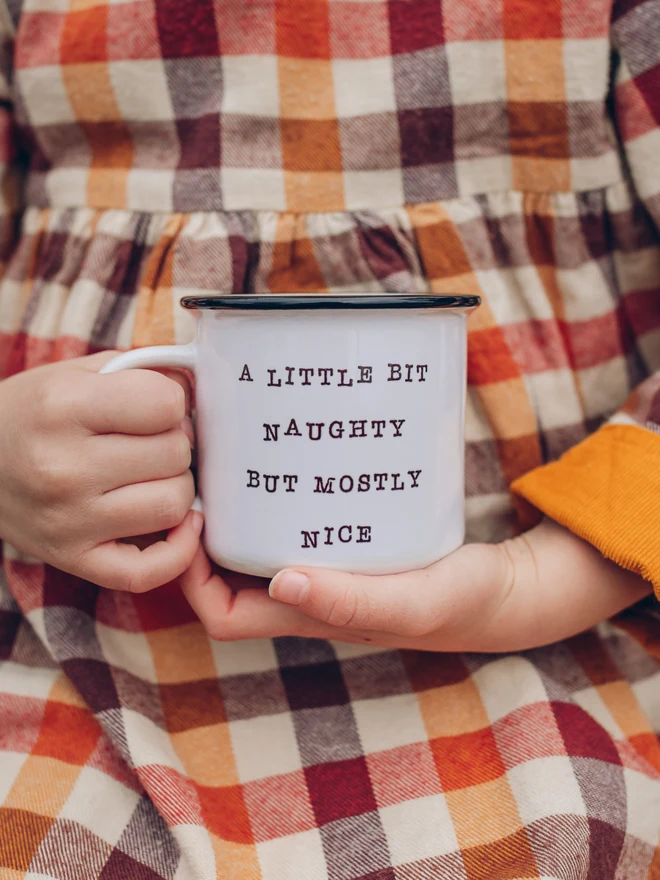 child holding christmas ceramic mug with words a little bit naughty but mostly nice