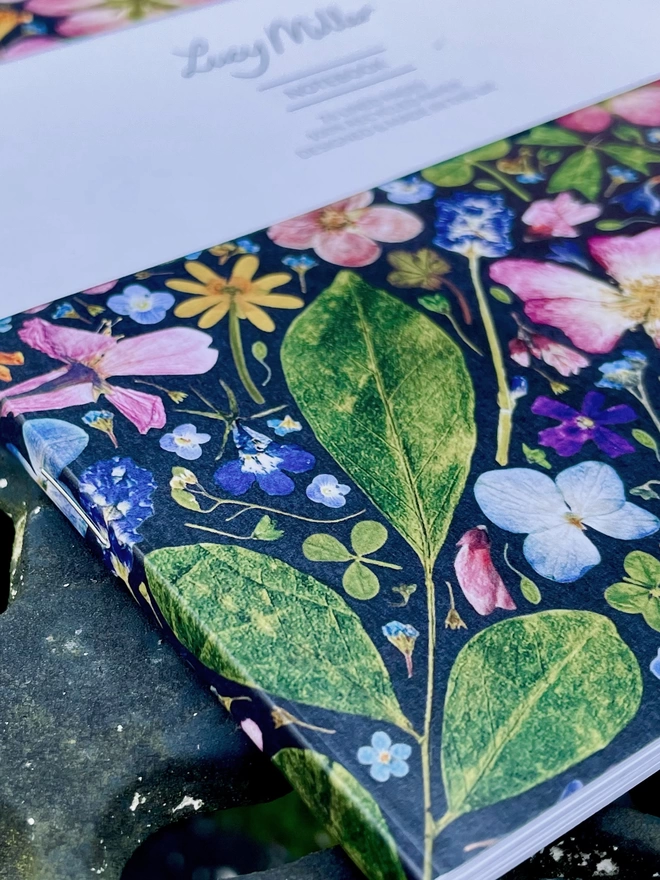Close-Up of Nature-Inspired Notebook with Elegant Pressed Floral Design, Stapled Spine, on Garden Table