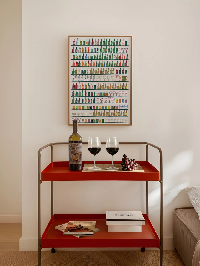 illustrated contemporary print featuring vibrant rows of drinks, bottles, wine & glasses. print shown framed against a cream wall.