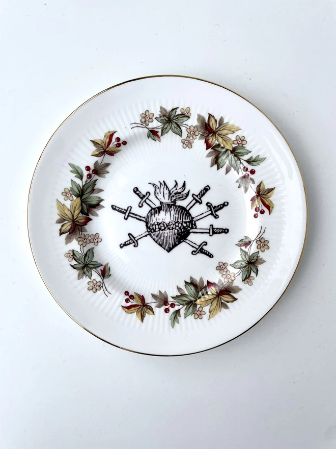 vintage plate with an ornate border, with a printed vintage illustration of a sacred heart in the middle 