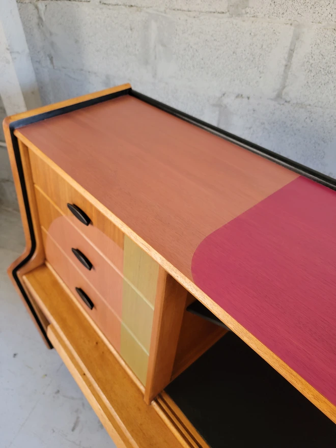 Top of a teak mid-century sideboard painted two tone pink shapes.