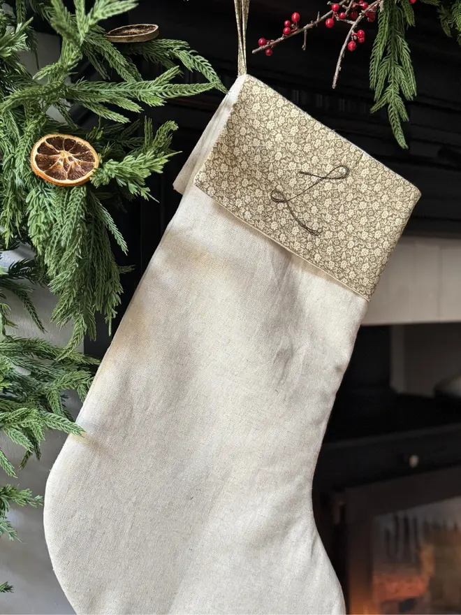 Floral Linen Christmas Stocking. Natural Linen Stocking with green floral cuff hung on a mantle