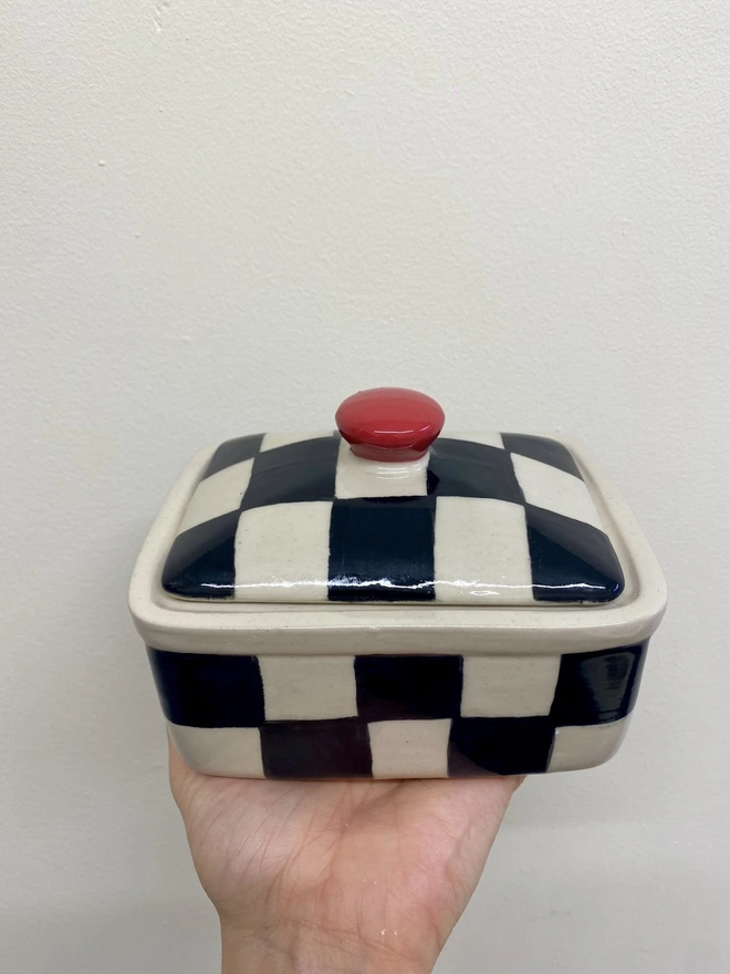  Checkered Black & Cream Handmade Ceramic Butter Dish, a black and white butter dish held against a white backdrop. 