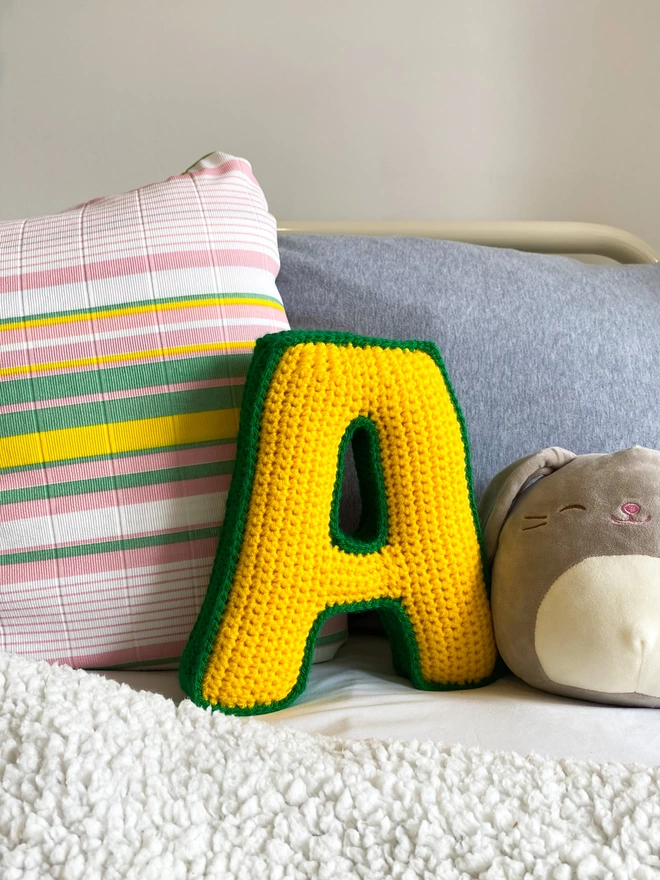 Crochet Letter A In Sunshine Yellow & Grass Green on childs bed