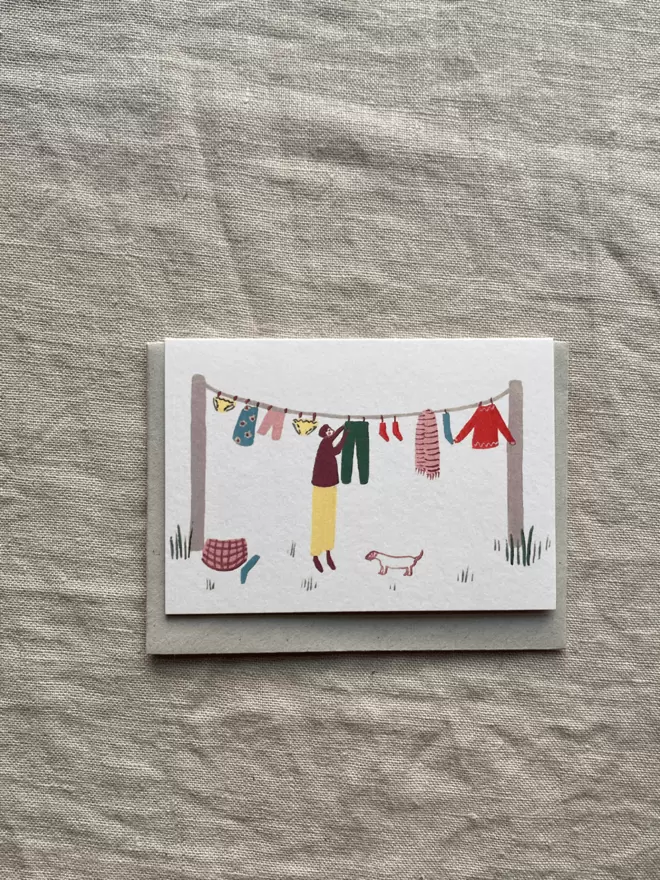 greetings card with someone hanging the washing out with a little dog watching.