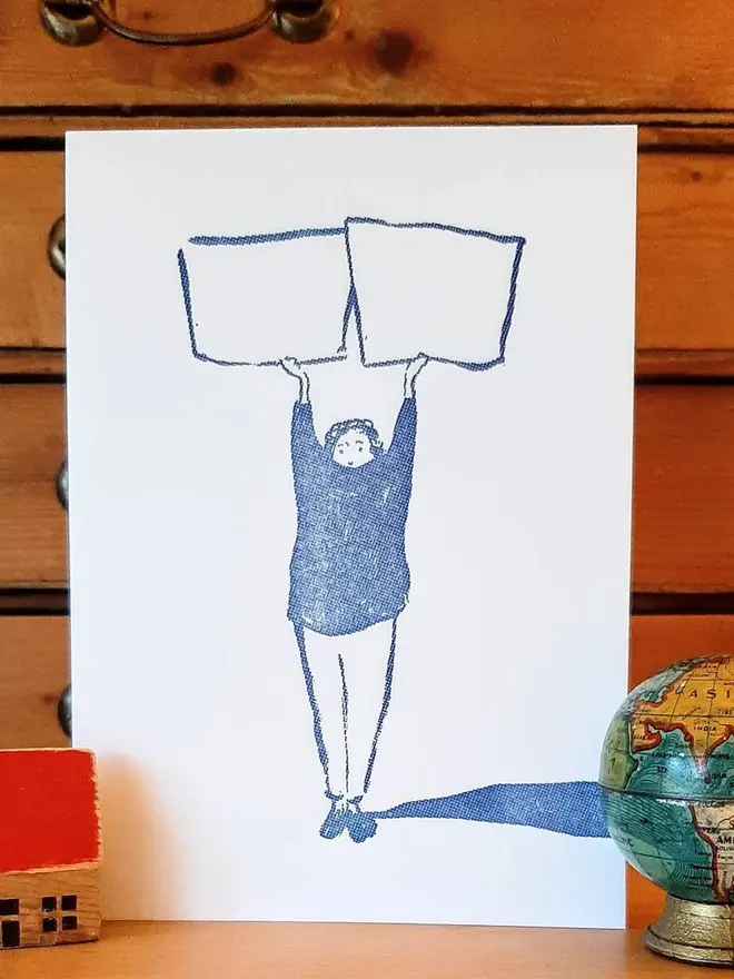 Blank Message Letterpress Handprinted Greetings Card, a white greetings card with a blue design sitting in front of a wooden background. 