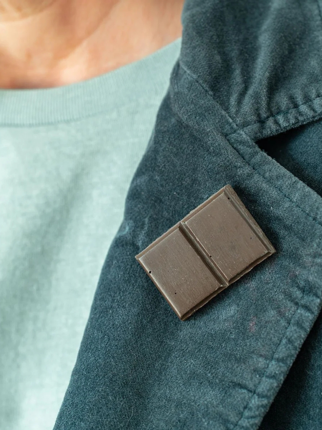 chocolate pin badges. a dark chocolate badge on a coat lapel.