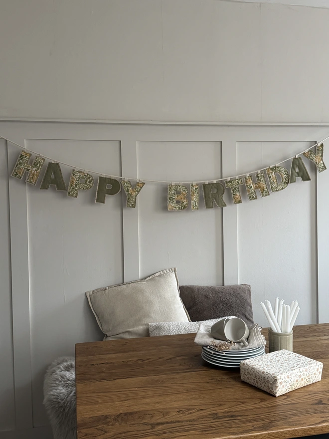 Floral printed Happy Birthday Letter Garland above a table with plates ready for an afternoon tea 
