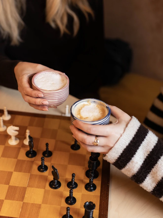 Striped coffee cups in the hands of two friends