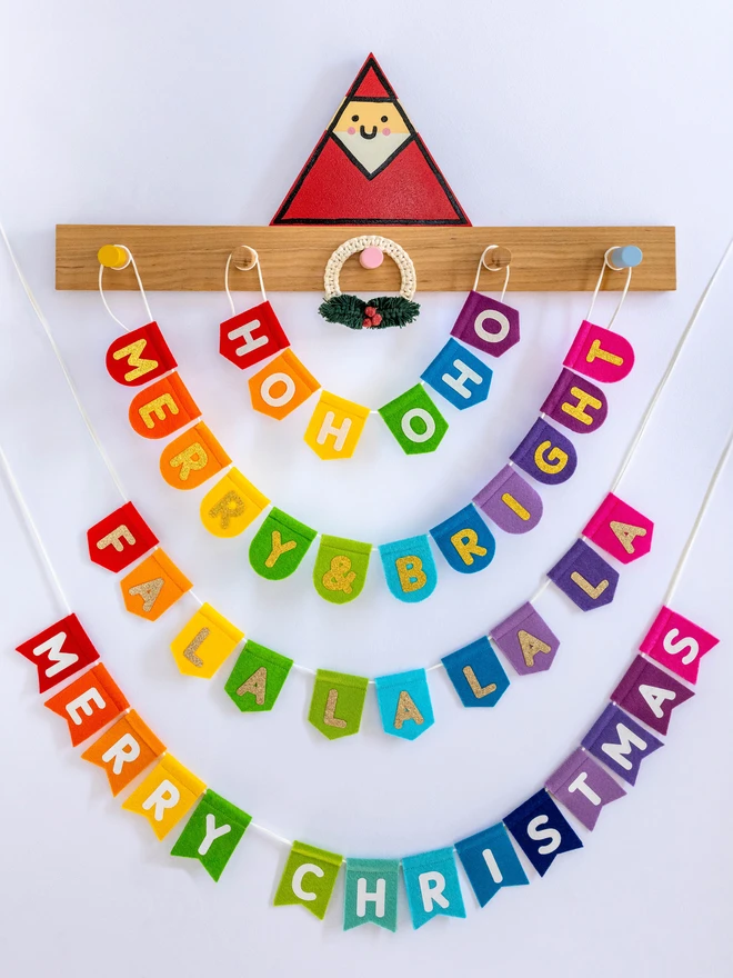 A range of felt, rainbow bunting, with glittery text. Each with a different Christmas phrase.