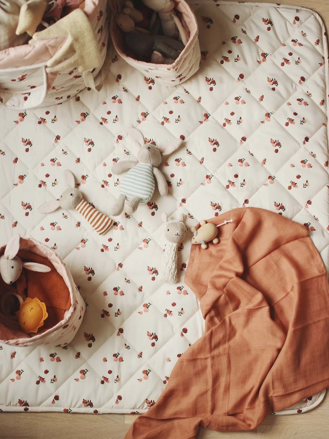 Muslins and rattles on a peachy play mat