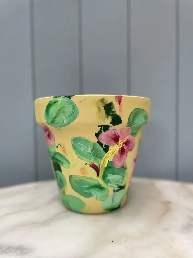 Unique hand-painted terracotta pot featuring apple blossoms on a pale blue background