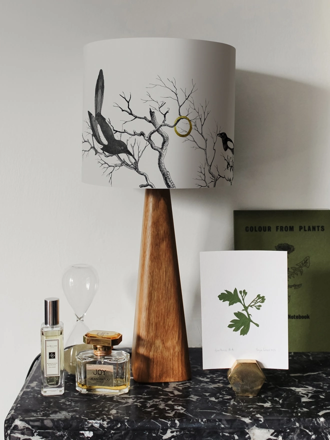 Handmade lampshade featuring cheeky magpies with gleaming gold details, inspired by traditional folklore and whimsical home decor.