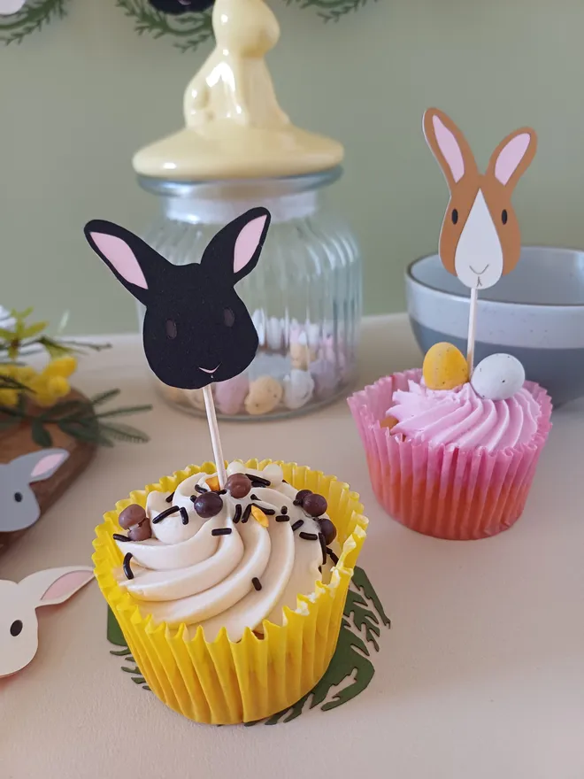 Close view of solid black Easter bunny cupcake topper in cupcake. Bunny has dark brown eyes and pale pink ears