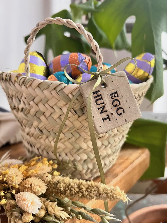 ceramic egg hunt tag, tied around the handle of a basket
