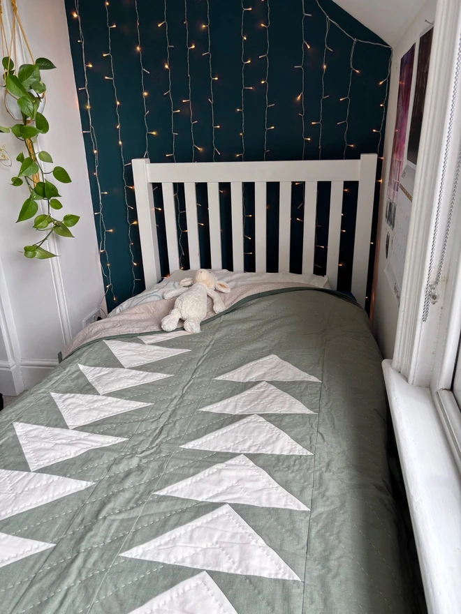 Flow Light Sage Green Linen Quilt. A green single quilt with geometric triangles on single bed.