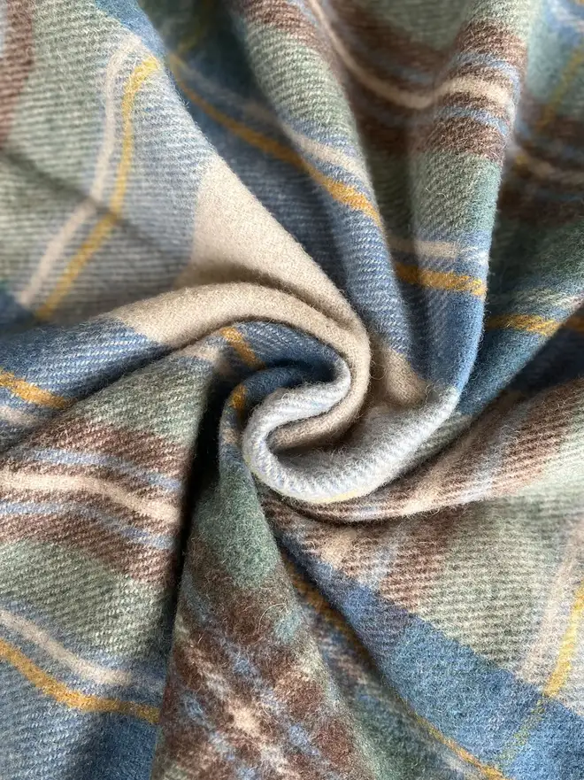 Stewart Muted Blue Blanket, a blue blanket curled up. 