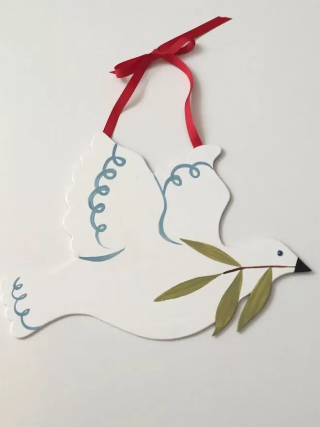 dove decoration with red ribbon hanging on white wall