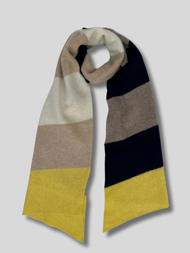 Knitted yellow oatmeal navy mushroom striped scarf shown flat on white background