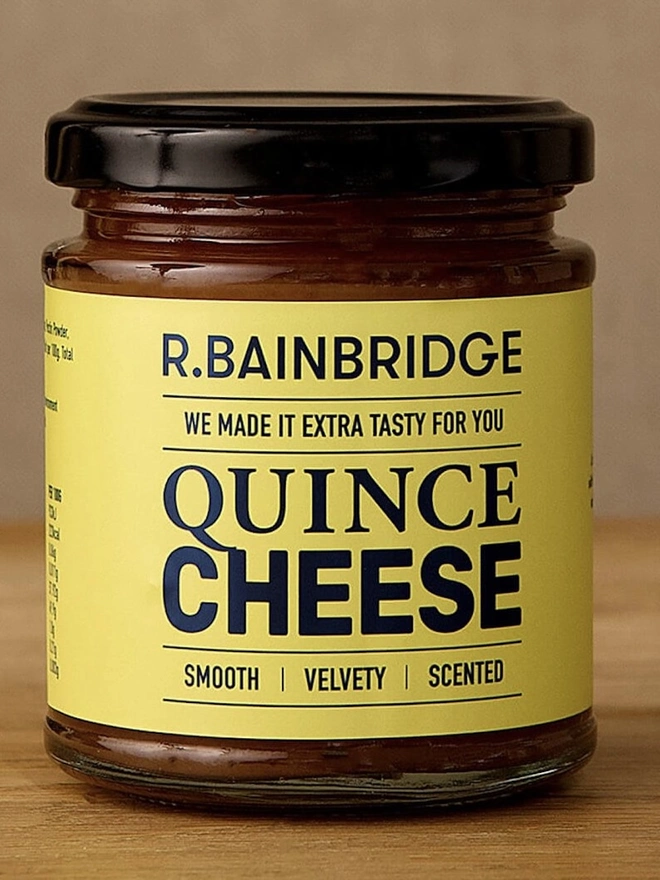 Norfolk Quince Cheese Chutney (Set Of 1, 2 Or 3), a jar of cheese chutney sitting on a wooden surface against a plain backdrop. 