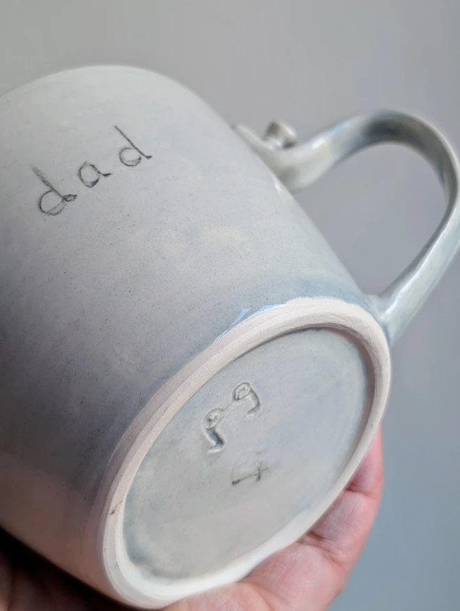 dad cup with grey glaze and a false ceramic screw holding the mug handle in place with the word dad on the front 