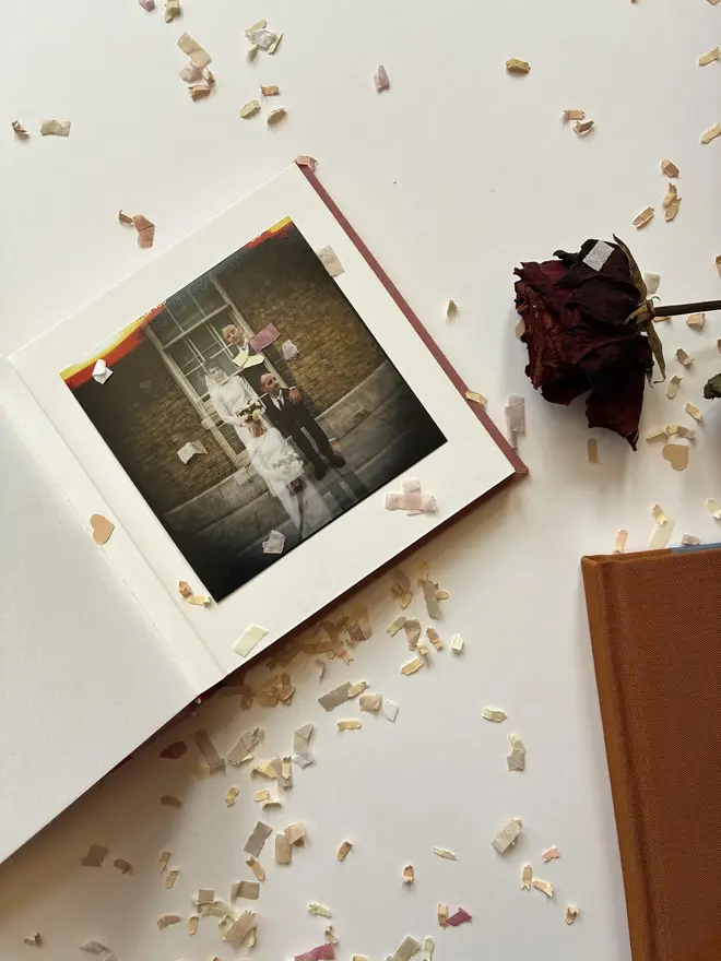 Open page of handmade instant photo guestbook by Keep Collect on confetti table