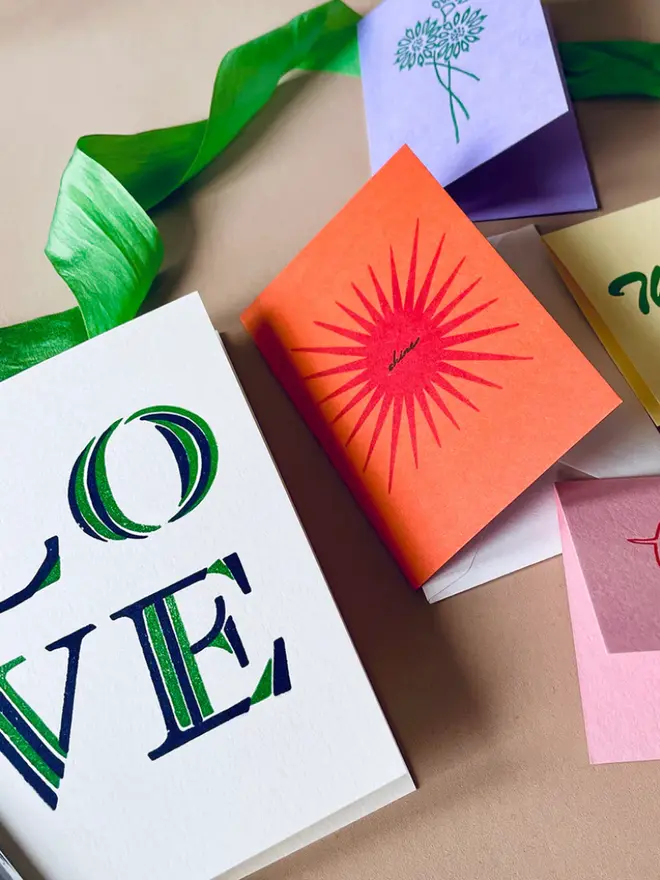 'Love' stripe hand printed card displayed on a table with other cards. 
