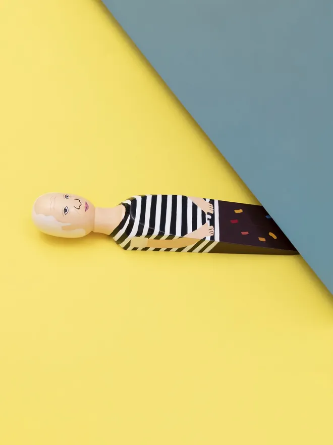 Wooden Door Stopper (Pabs), a colourful wooden door stop sitting under a door.