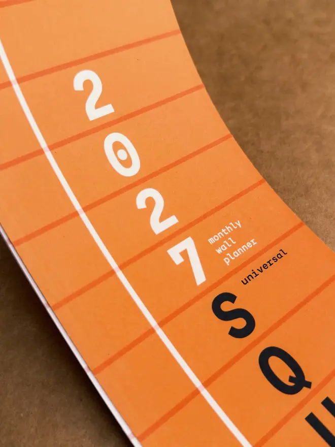 Closeup of orange Squared: 2027 Monthly Wall Calendar, showing the title page