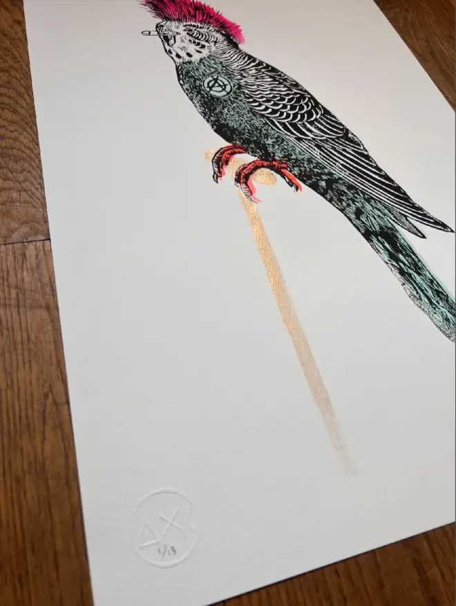 Punk budgie lino print, with symbols, coloured with blue and pink paint with on a white background. 