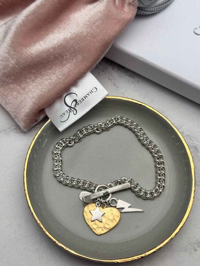 large gold heart charm and silver mini bolt and star charms on sterling silver chunky curb charm bracelet with silver t bar fastener. gift box and pouch