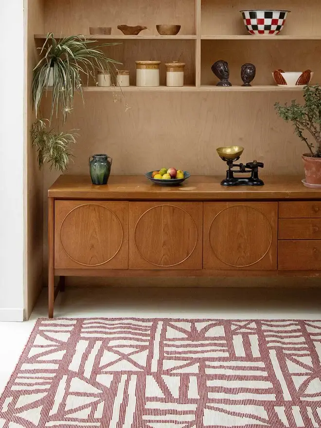 Tudor Flatweave Rug, a colourful rug in a living room. It is surrounded by other household items. 