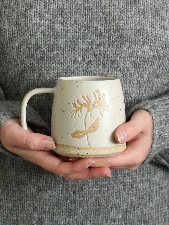 Hands holding honeysuckle mug