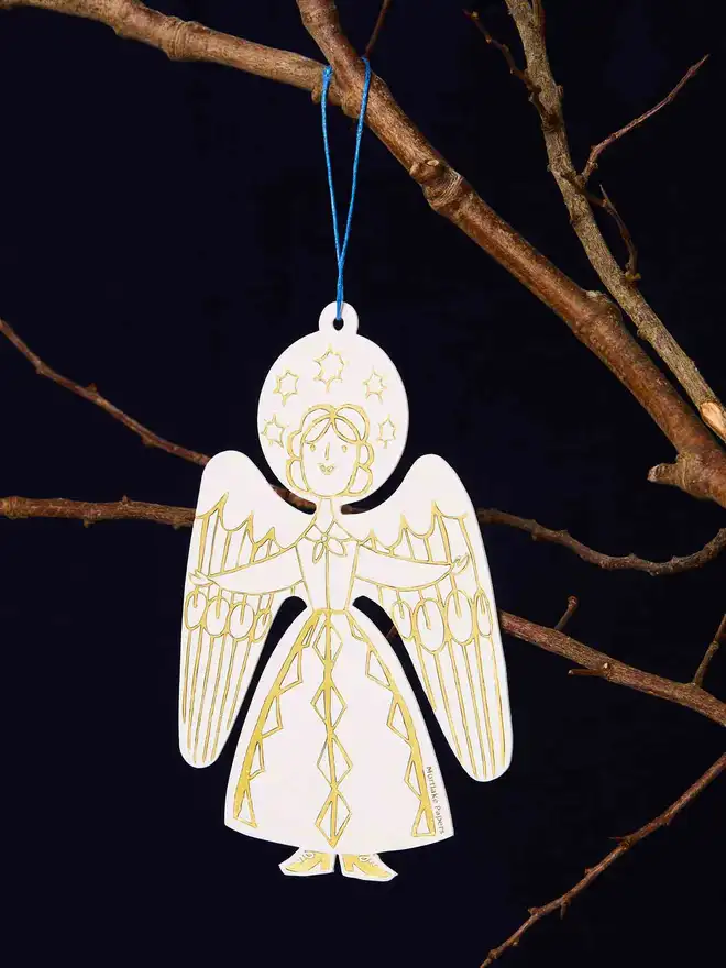 Decorative angel ornament hanging from a branch against a dark background