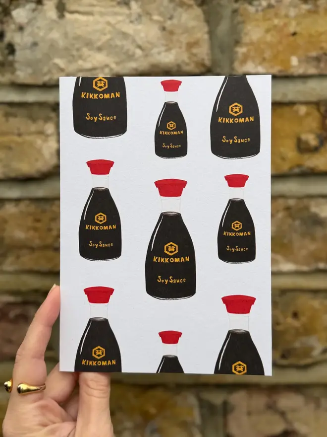 soy sauce bottles illustrated card.  card photographed against brick wall backdrop.