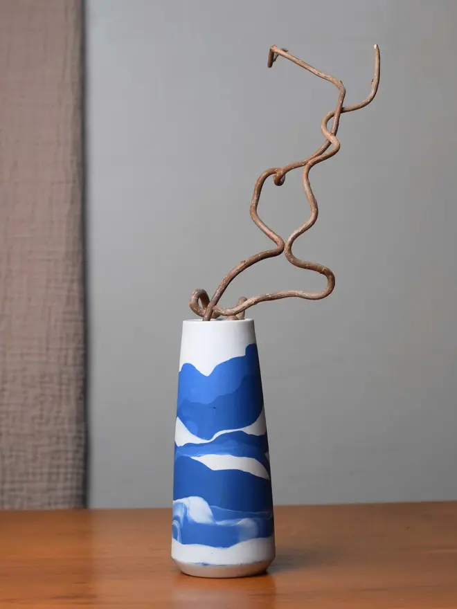 vase on wooden table, vase has streaky pattern in shades of bluee