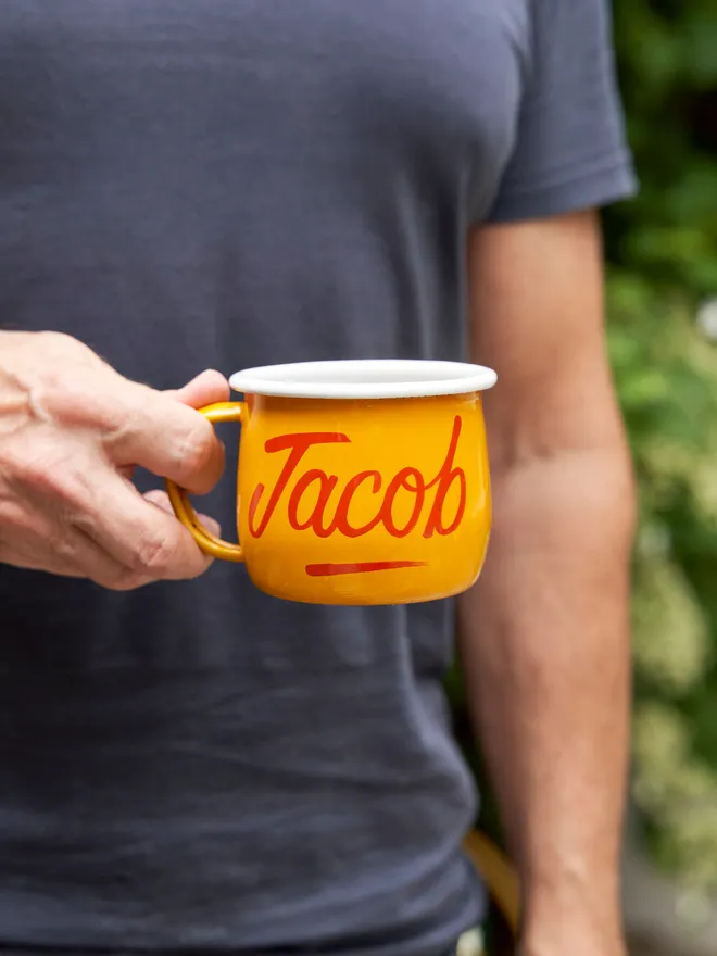 man holding yellow mug with 'jacob' script text