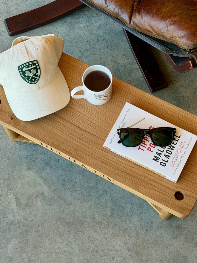 Overhead view of the personalised oak swing seat used as a side table with book and coffee