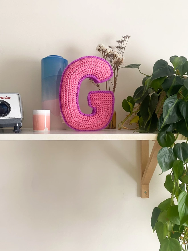 Crochet cushion shaped like the letter G in Pink and Magenta