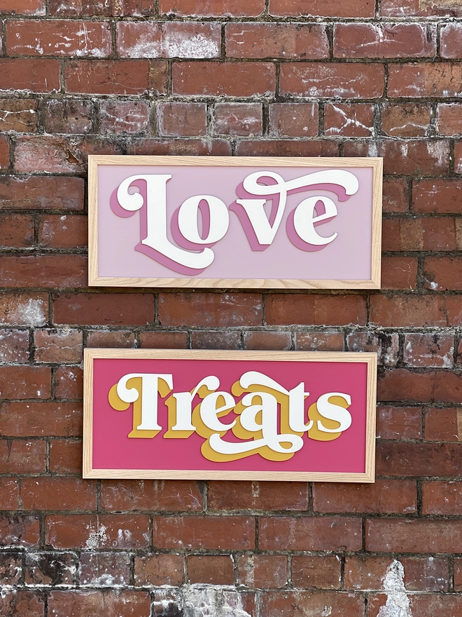 2 painted wooden signs which read LOVE & Treats on a brick wall 