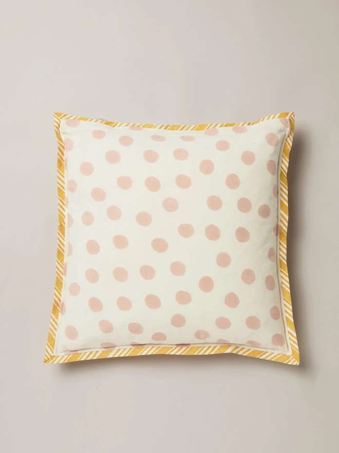 Reverse of block printed cushion in a pink block printed spot over a cream background, with a cream and yellow stripe border