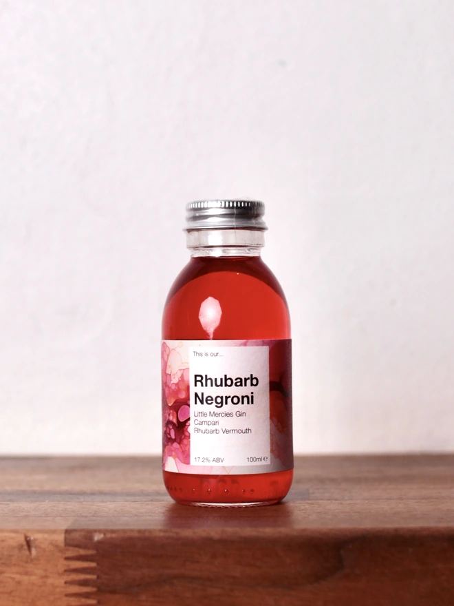 Mini Rhubarb Negroni on a wooden shelf