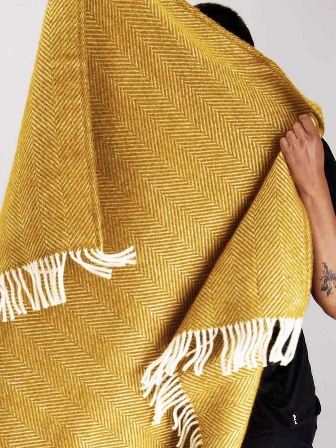 Organic Wool Throw, a person with the wool throw draped over them. 