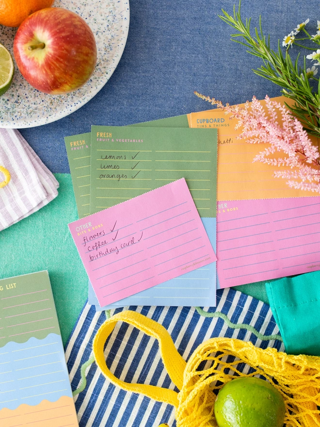 The colourful Raspberry Blossom tear of shopping list on a busy kitchen table