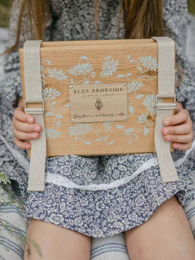 Wooden Flower Press with Straps - Daisy Chain child holding the flower press so we see the front on their lap