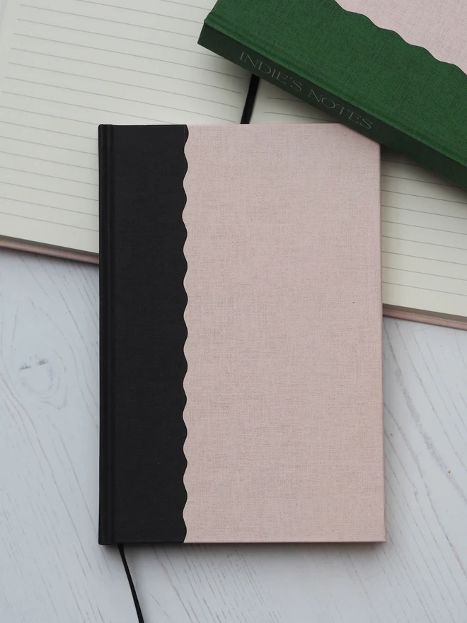 a two tone hardcover notebook with a scallop design in linen black and blush 