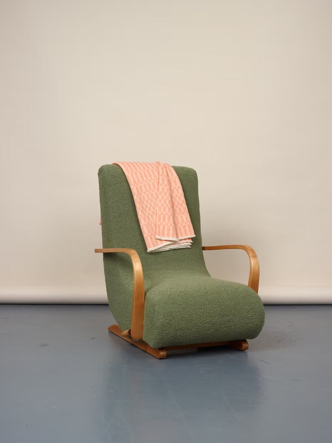 arabella lambswool blanket. a textured pink blanket thrown over a green chair.
